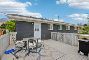 Exterior deck featuring a white railing system, dark brick siding, and multiple windows