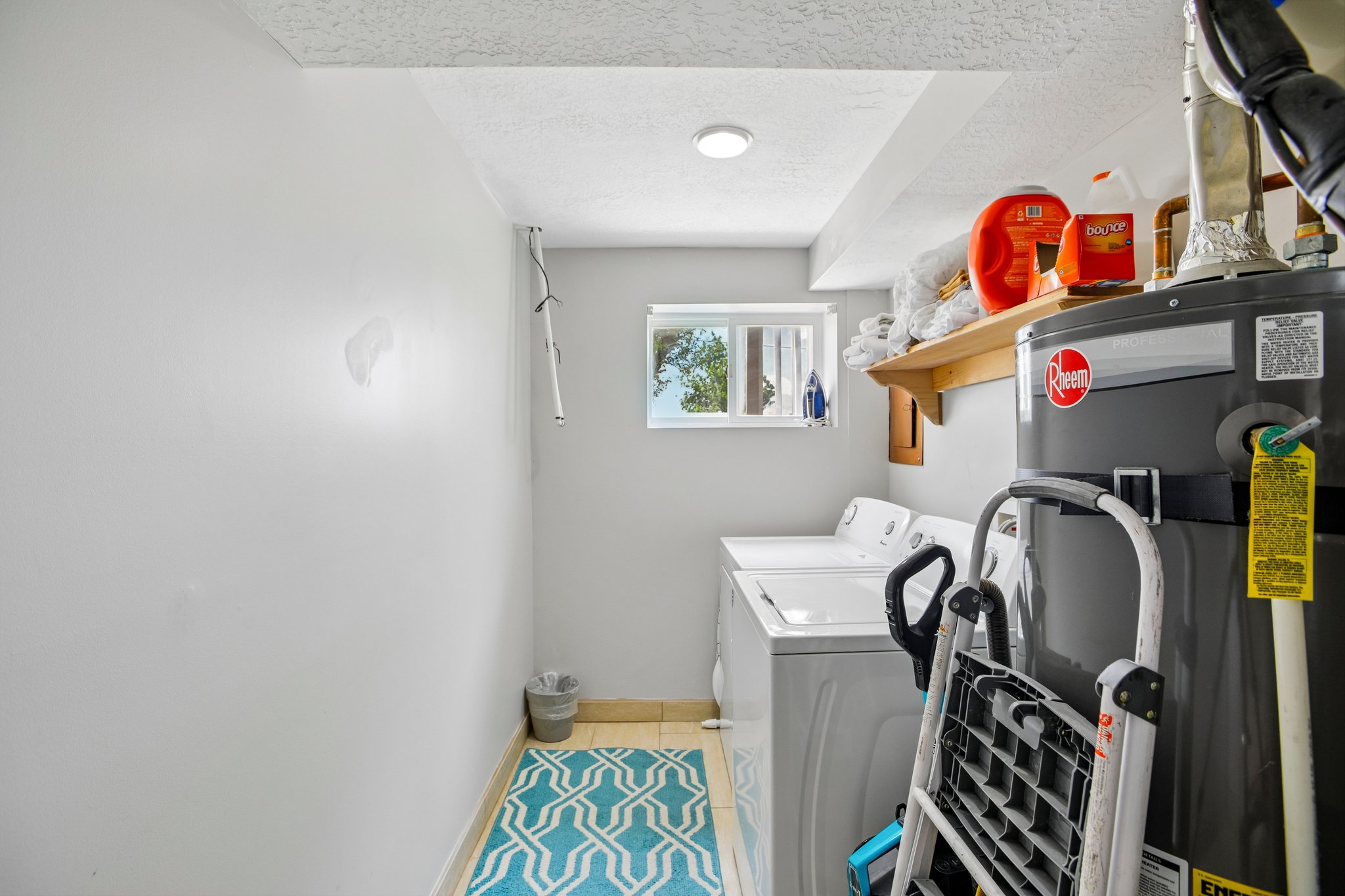 Dedicated laundry area featuring a window, overhead lighting, and wall shelving