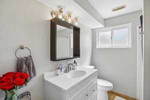 Bathroom featuring a white vanity with an integrated sink, brushed nickel faucet, and a coordinating mirror with overhead lighting
