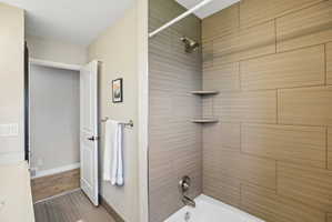 Bathtub with subway tile surround featuring integrated corner shelving, a bronze finish showerhead, and a chrome-finish faucet