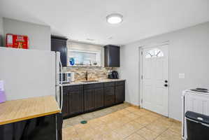 Modern kitchen featuring dark wood-finish cabinetry, light-toned tile flooring, and a window above the sink