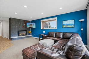 Living area with a stone-surround fireplace, a large picture window, recessed lighting, and a wood-finish flooring entry