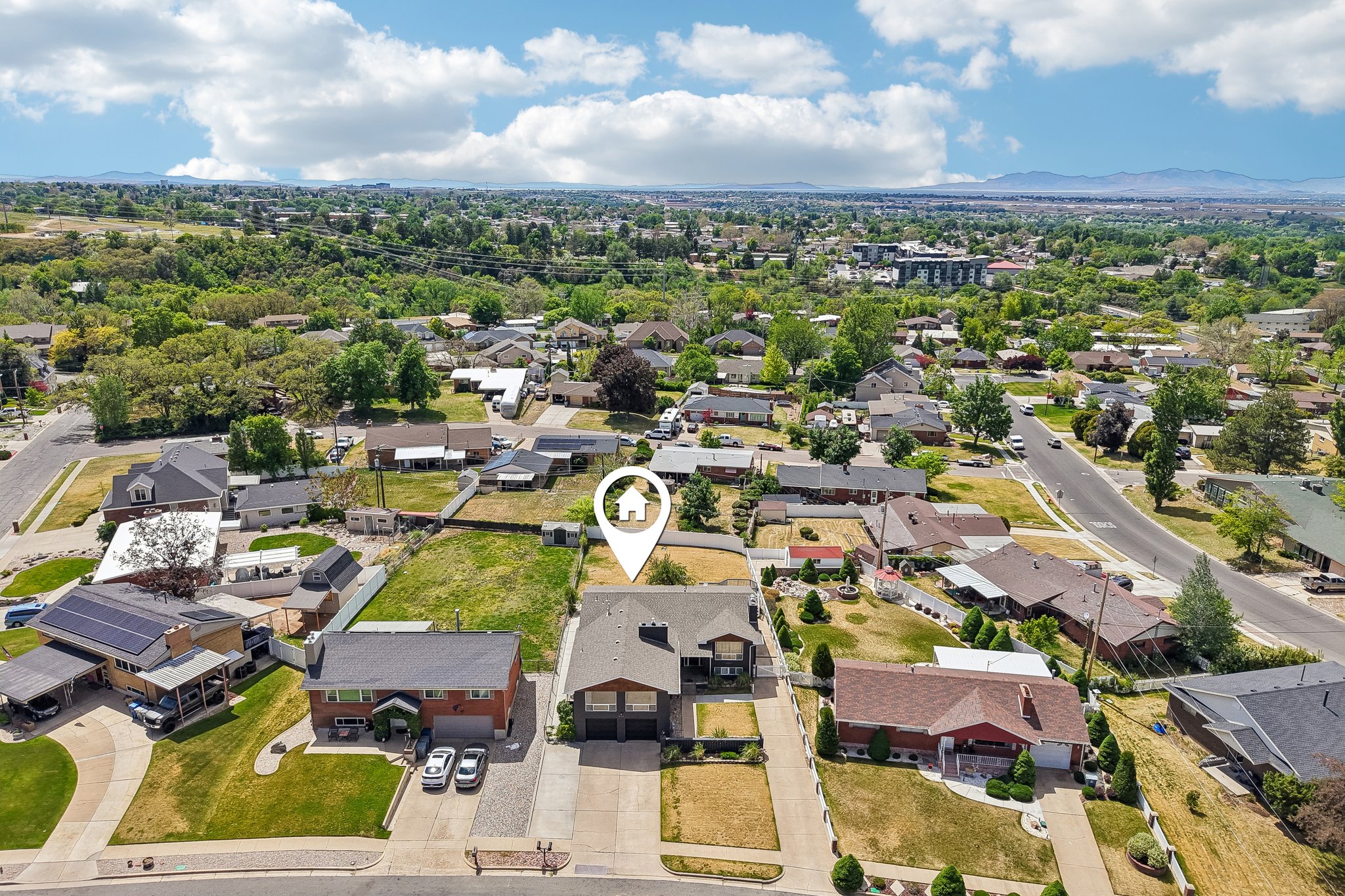 Residential neighborhood featuring a variety of architectural styles, mature trees, and mountainous terrain in the distance