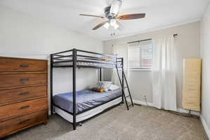 Bedroom featuring neutral wall paint, carpet flooring, a window with horizontal blinds, and a ceiling fan with integrated lighting