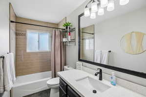 Bathroom featuring a white tub, light-colored tile surround with decorative accent band, and a white framed window