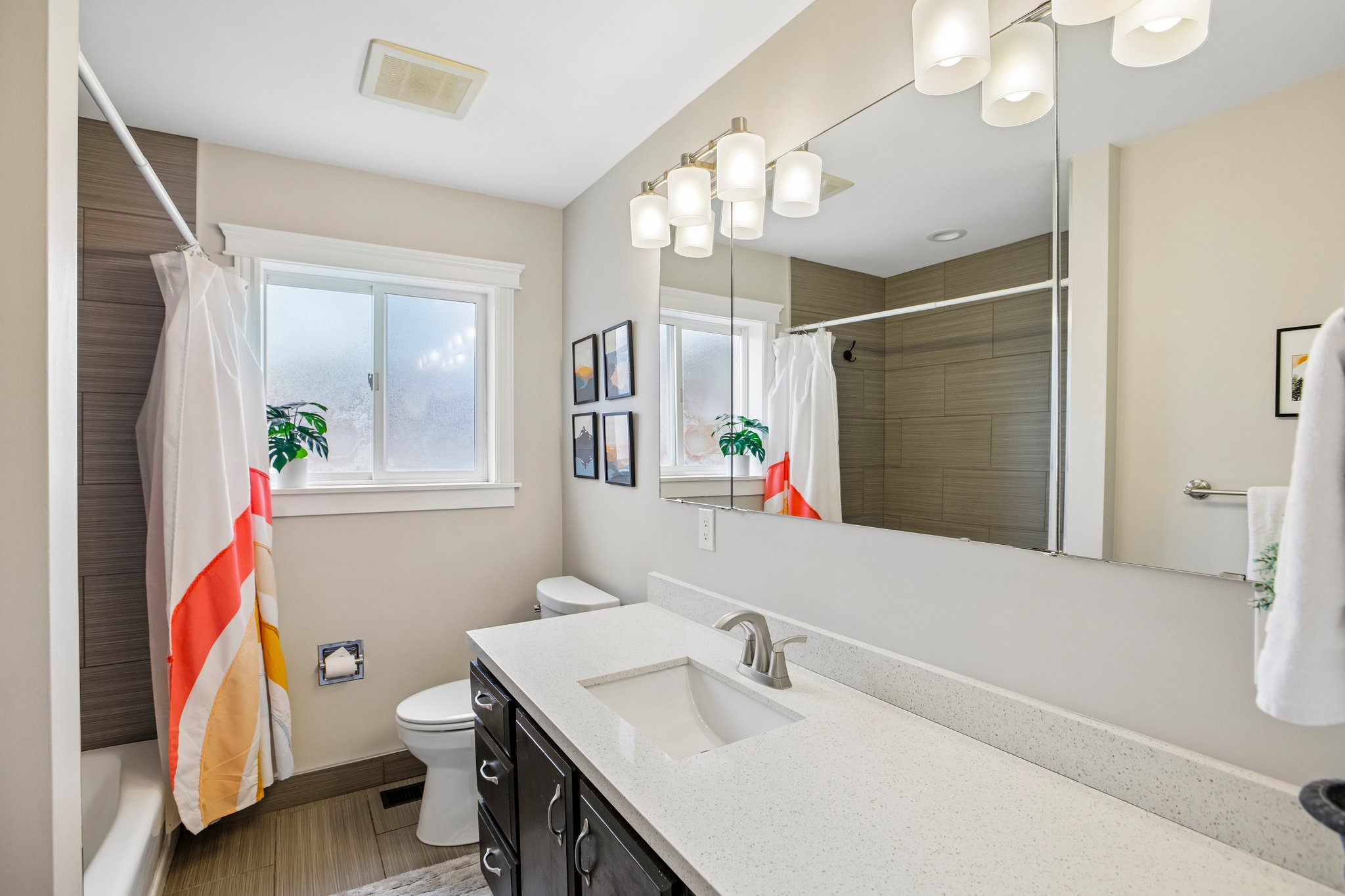 Bathroom featuring a single vanity with dark cabinetry, integrated sink, and light-toned countertop