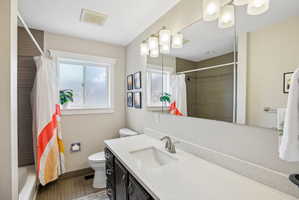 Bathroom featuring a single vanity with dark cabinetry, integrated sink, and light-toned countertop