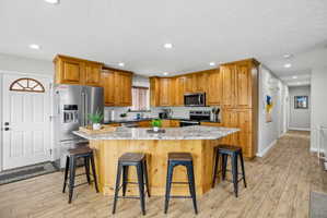 Kitchen featuring wood cabinetry, stainless steel appliances, and a central island with a light-toned countertop