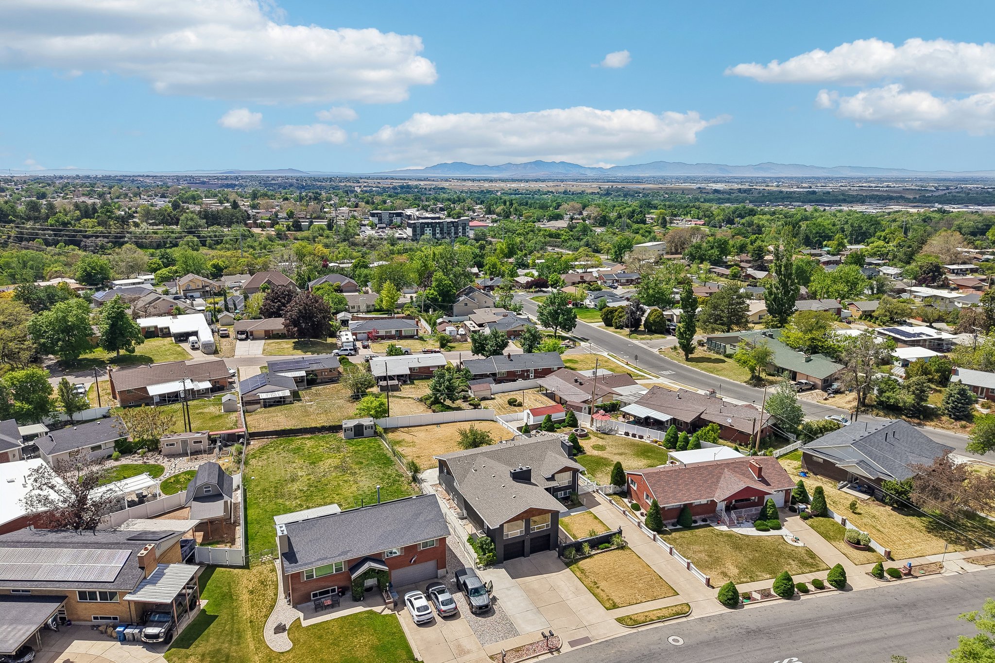 Aerial perspective showcasing a residential neighborhood with established trees and distant mountain ranges