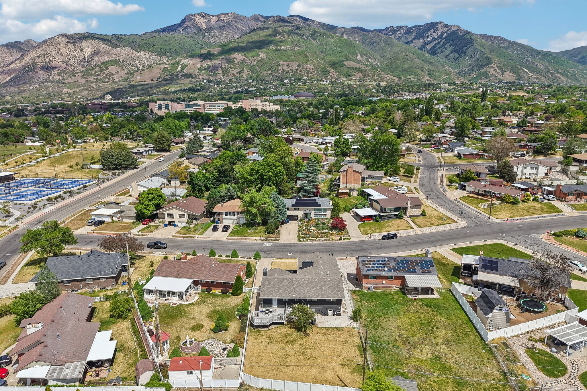 Residential neighborhood featuring a variety of single-family homes, mature trees, and mountainous terrain in the background