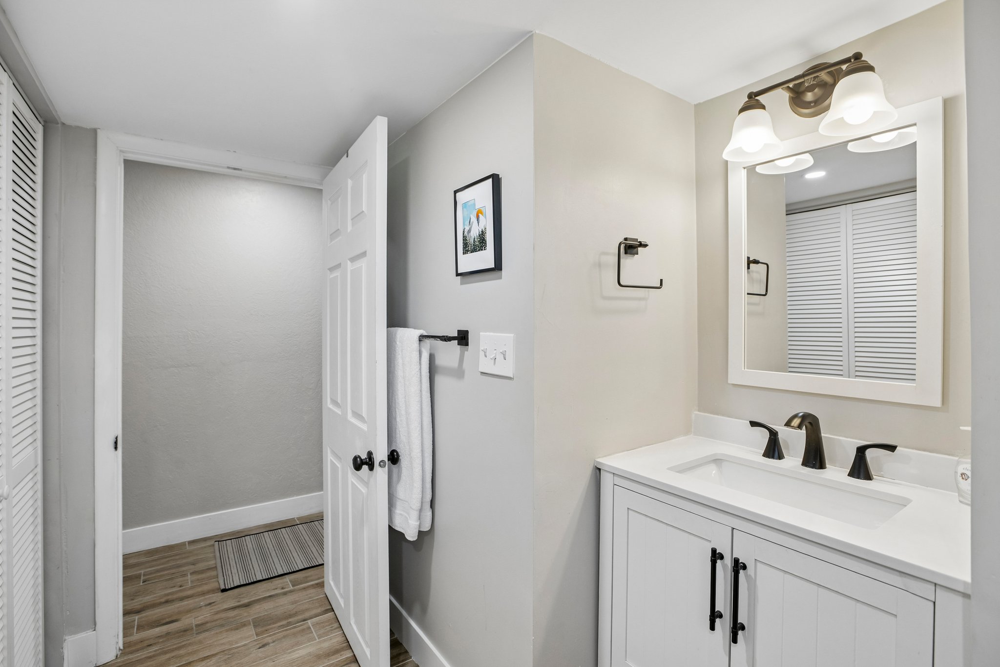 Bathroom featuring a white vanity with a rectangular sink, matte black faucet, and white countertop