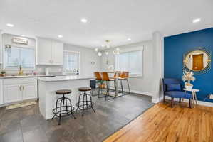 Open-concept kitchen and dining area featuring white cabinetry, light-colored countertops, and a kitchen island with seating