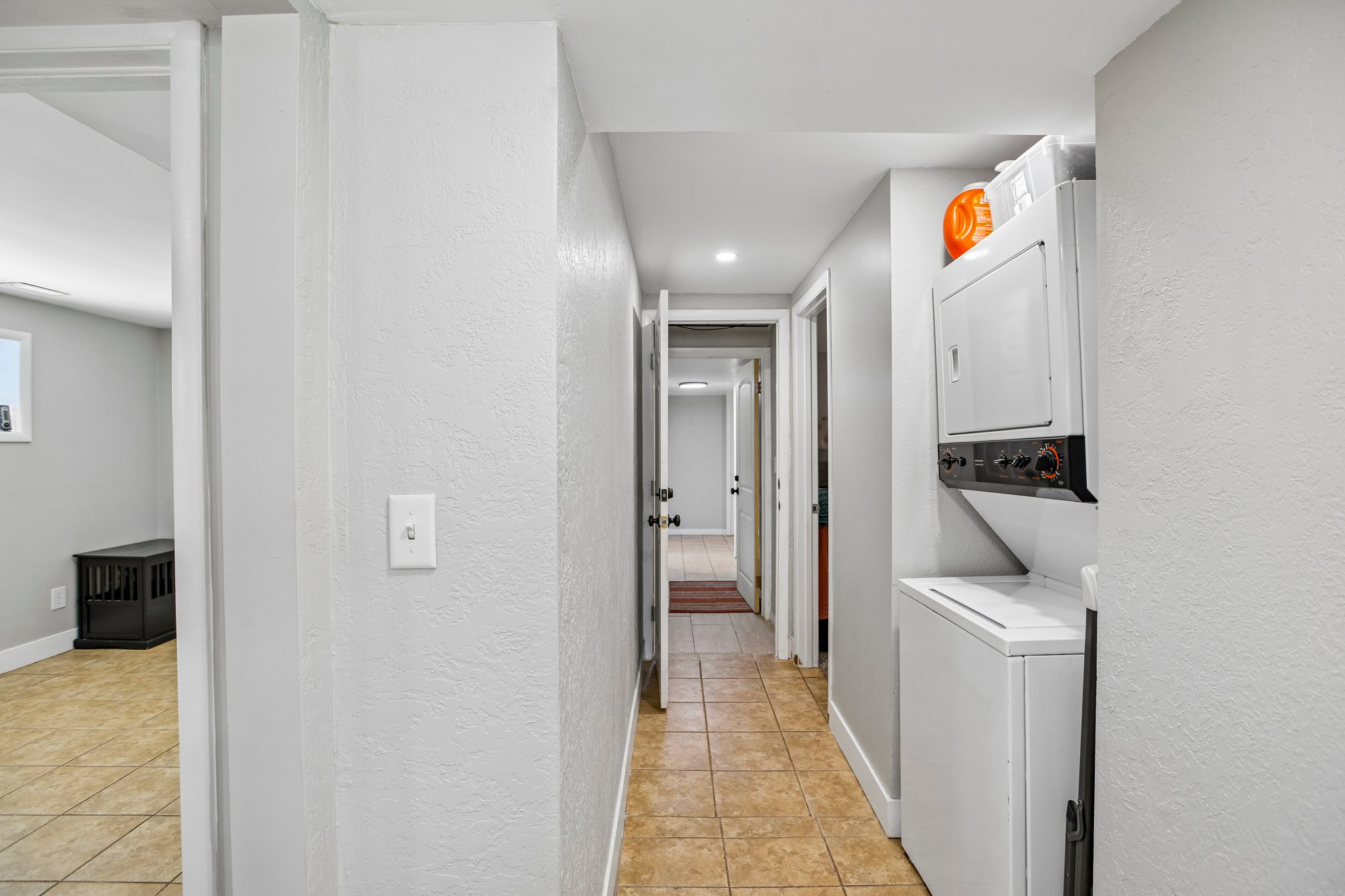 Hallway featuring tile flooring, recessed lighting, and a stacked washer and dryer unit