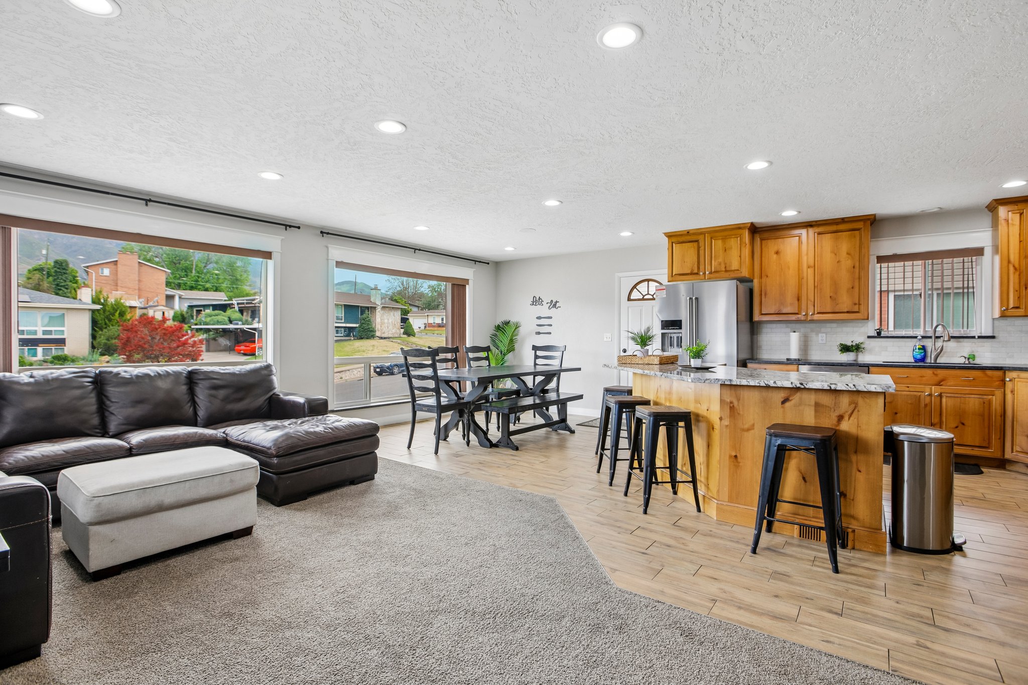Open-concept living area featuring a kitchen with wood cabinetry, granite countertops, and a central island with bar seating