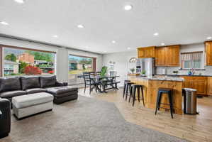 Open-concept living area featuring a kitchen with wood cabinetry, granite countertops, and a central island with bar seating