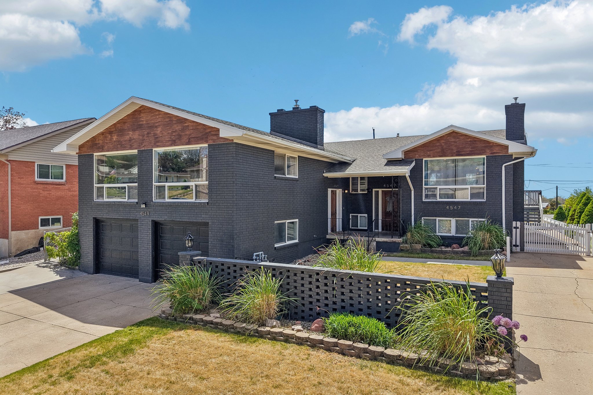 Two-story brick exterior with a dark finish, featuring a prominent two-car garage with black doors