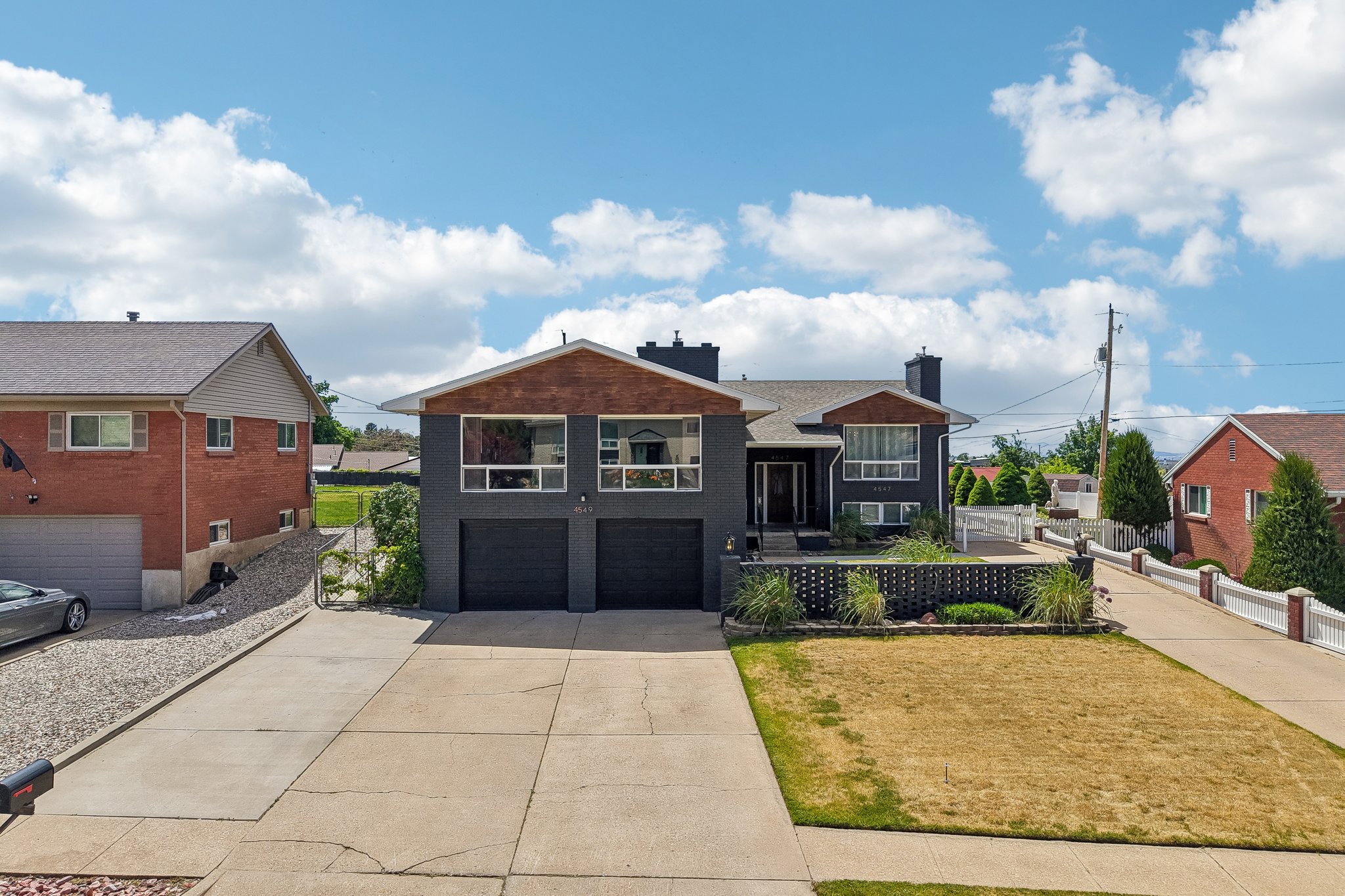 Contemporary split-level residence featuring a dark gray facade with contrasting wood-finish accents