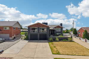 Contemporary split-level residence featuring a dark gray facade with contrasting wood-finish accents