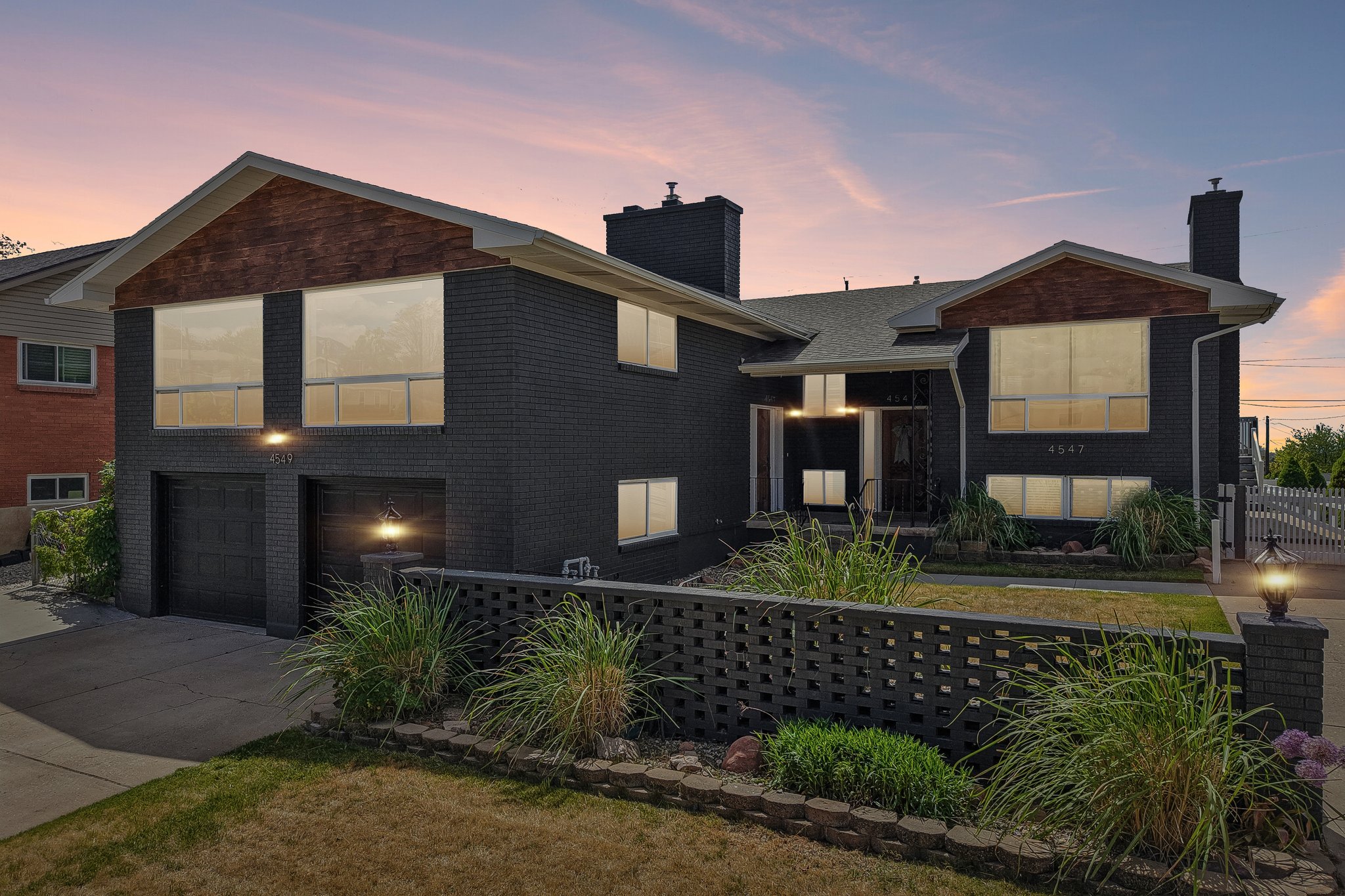 Contemporary split-level residence featuring dark brick exterior and complementary wood-finish gables