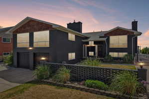 Contemporary split-level residence featuring dark brick exterior and complementary wood-finish gables
