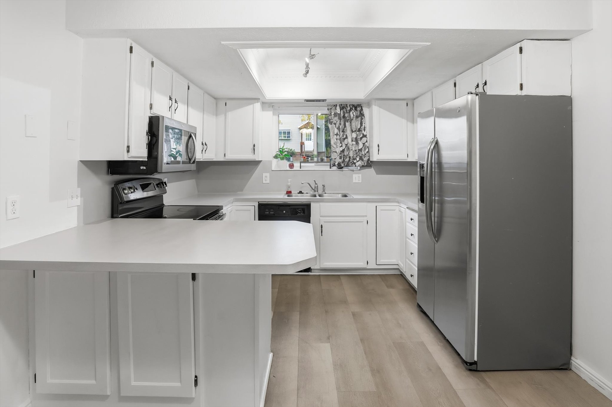 Kitchen featuring white cabinetry, light-toned countertops, and wood-finish flooring