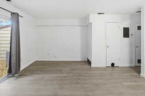 Spacious room featuring light wood-finish flooring, white walls, and a sliding glass patio door