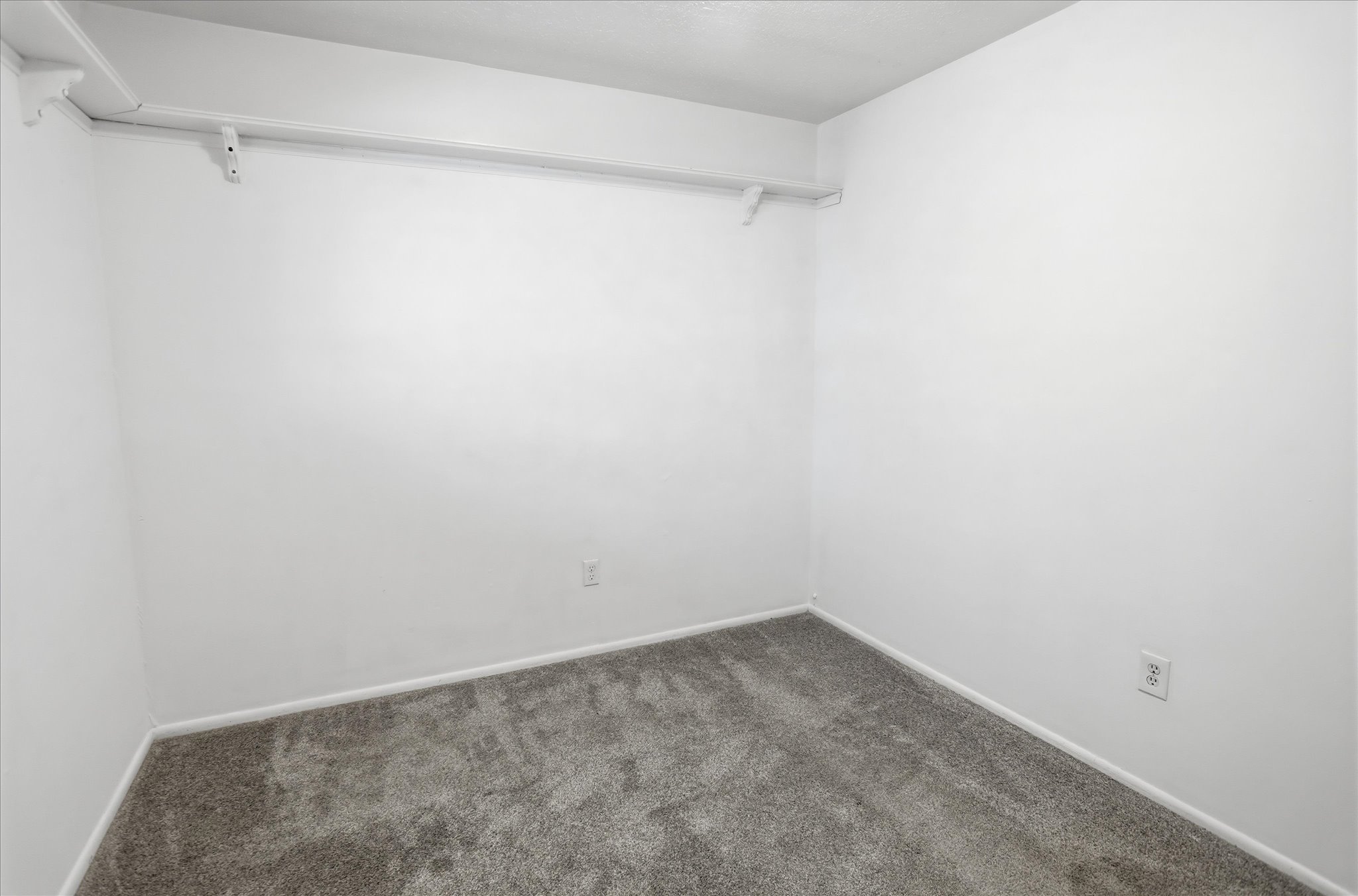 Interior room featuring light gray carpeting, white baseboards, and white painted walls