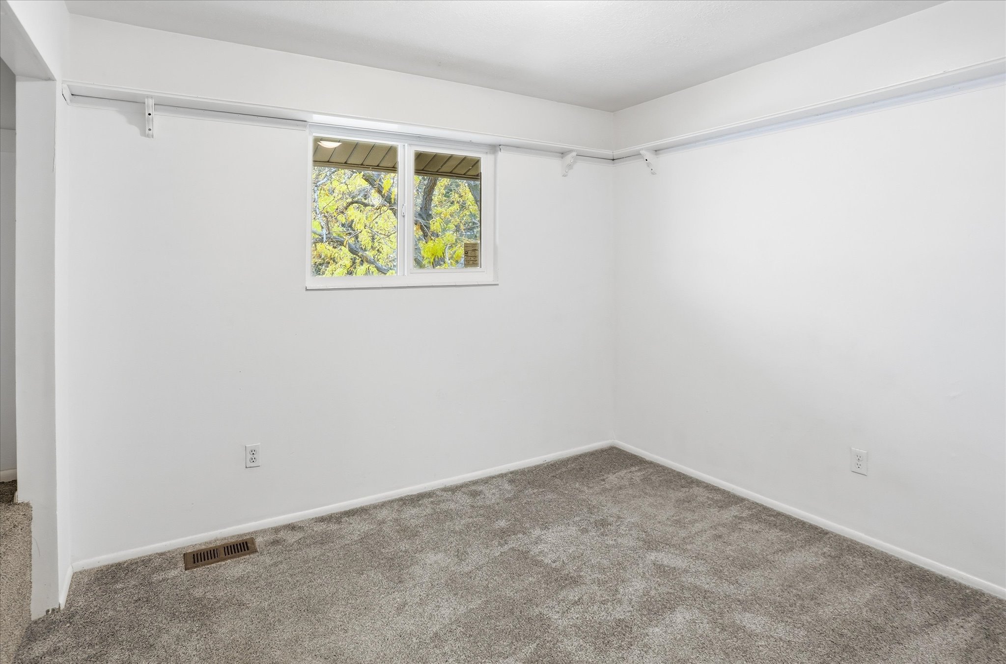Room featuring neutral wall paint, gray carpet, a double-paned window, and a wall-mounted track system