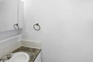 Bathroom vanity featuring an oval undermount sink, a mottled countertop, and a mirrored medicine cabinet with an integrated shelf