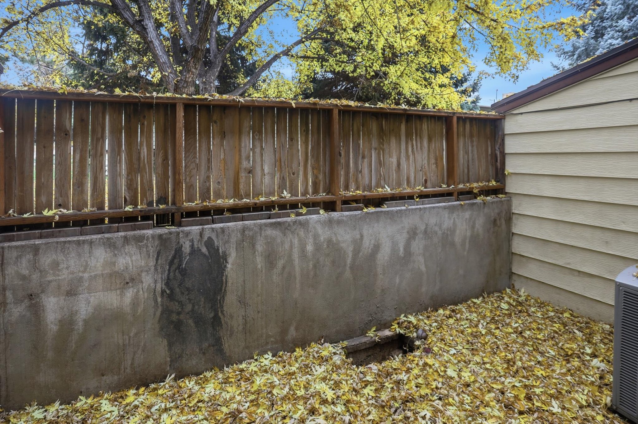Wood fence atop a concrete retaining wall bordering the property
