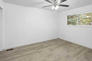 Bright interior space featuring wood-finish flooring, white walls, and a ceiling fan with integrated lighting