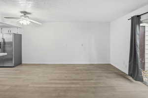 Open-concept living space featuring wood-finish flooring, white walls, and a ceiling fan