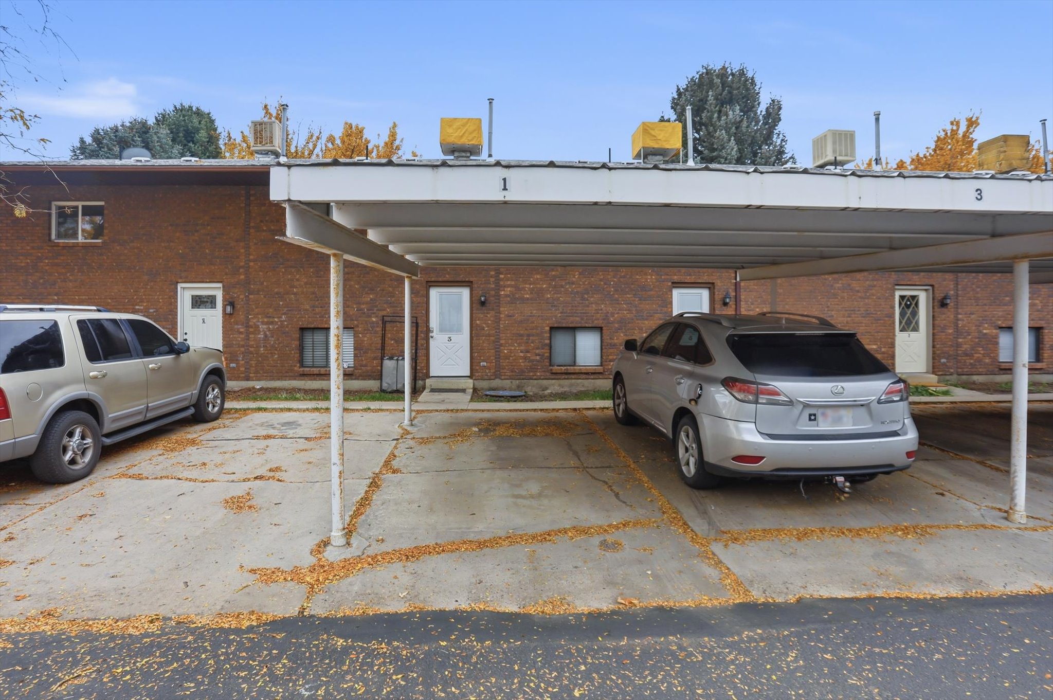 Brick exterior multi-unit building with individual entry doors and a covered parking area