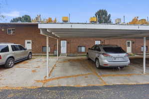 Brick exterior multi-unit building with individual entry doors and a covered parking area