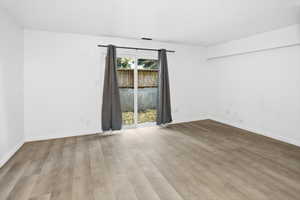 Spacious room featuring new wood-finish flooring, white walls, and bright white trim