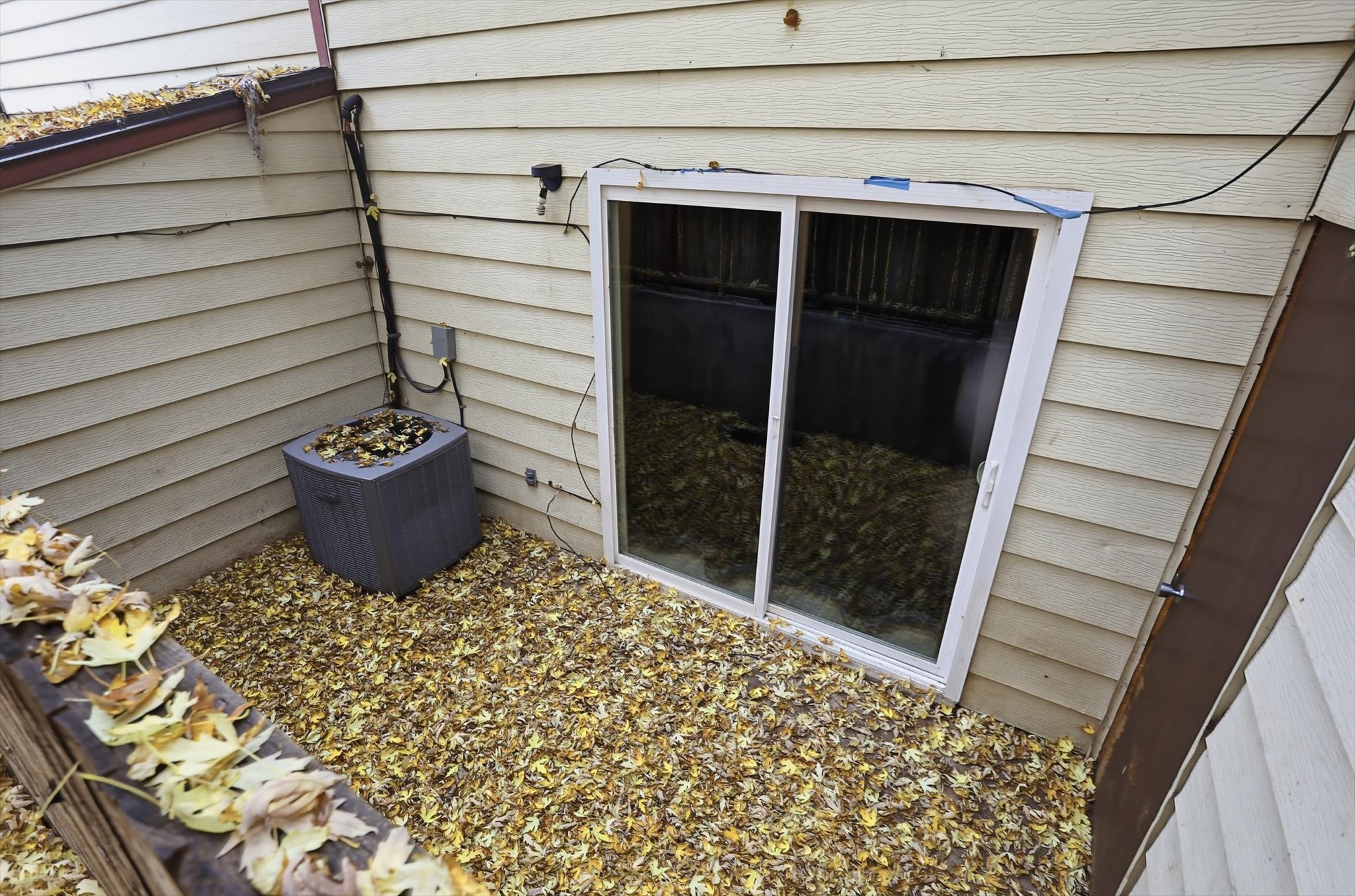 Basement-level exterior featuring light-colored horizontal siding and a white-framed sliding glass door