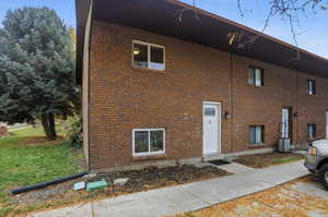 Brick exterior featuring white trim windows and a white entry door