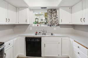 Kitchen featuring white cabinetry, light countertops, and a double basin stainless steel sink with a window overhead