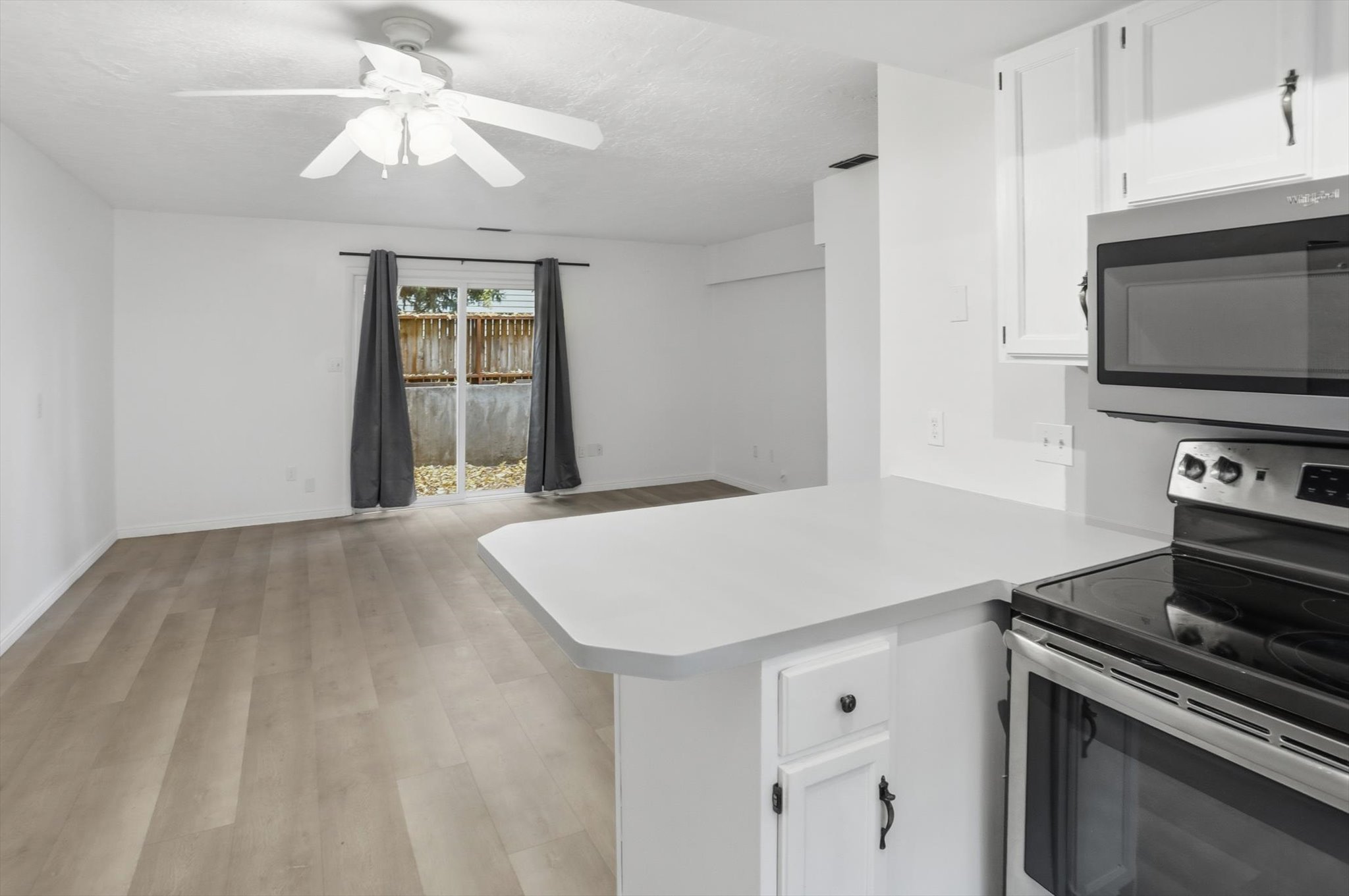 Open-concept living space featuring wood-finish flooring, a ceiling fan, and sliding glass doors