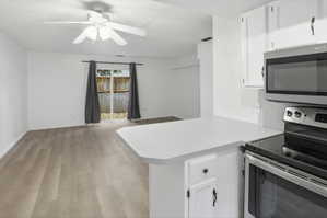 Open-concept living space featuring wood-finish flooring, a ceiling fan, and sliding glass doors