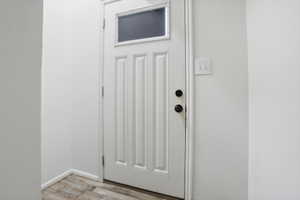 White paneled door with an upper window insert, featuring black hardware and wood-finish flooring