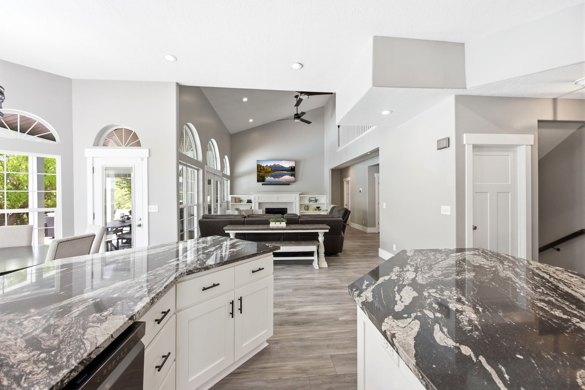 Kitchen island with a dark granite countertop, white cabinetry, and matte black hardware