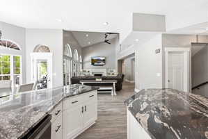 Kitchen island with a dark granite countertop, white cabinetry, and matte black hardware