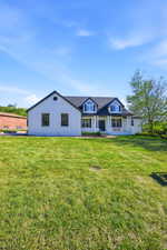 White facade residence featuring a prominent gabled roofline with dormer windows and black shutters