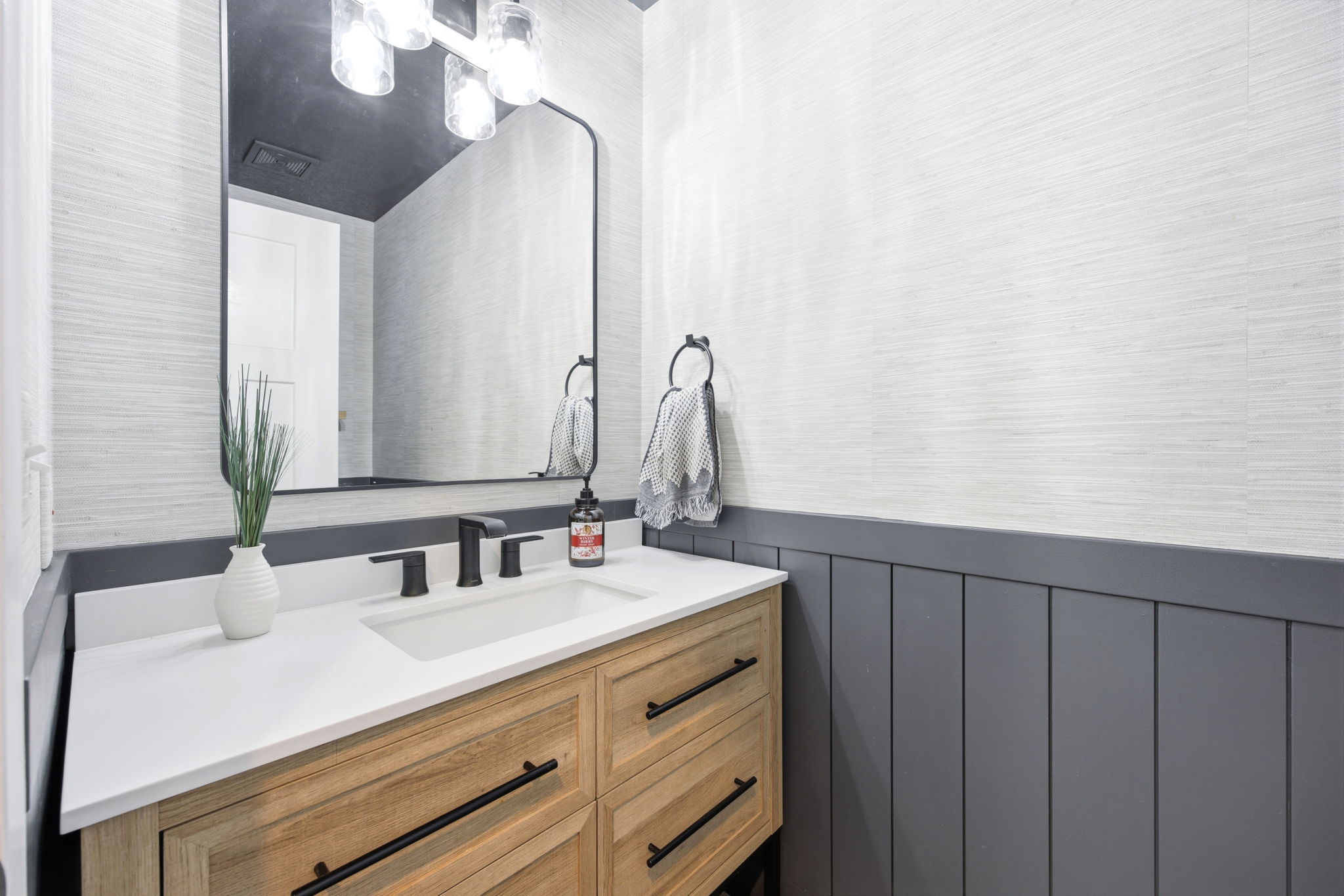 Modern vanity with a white countertop and integrated sink, featuring a matte black faucet