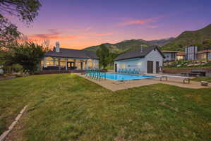 Expansive exterior featuring a swimming pool, pool house, diving board, and a primary residence with arched windows and a covered patio
