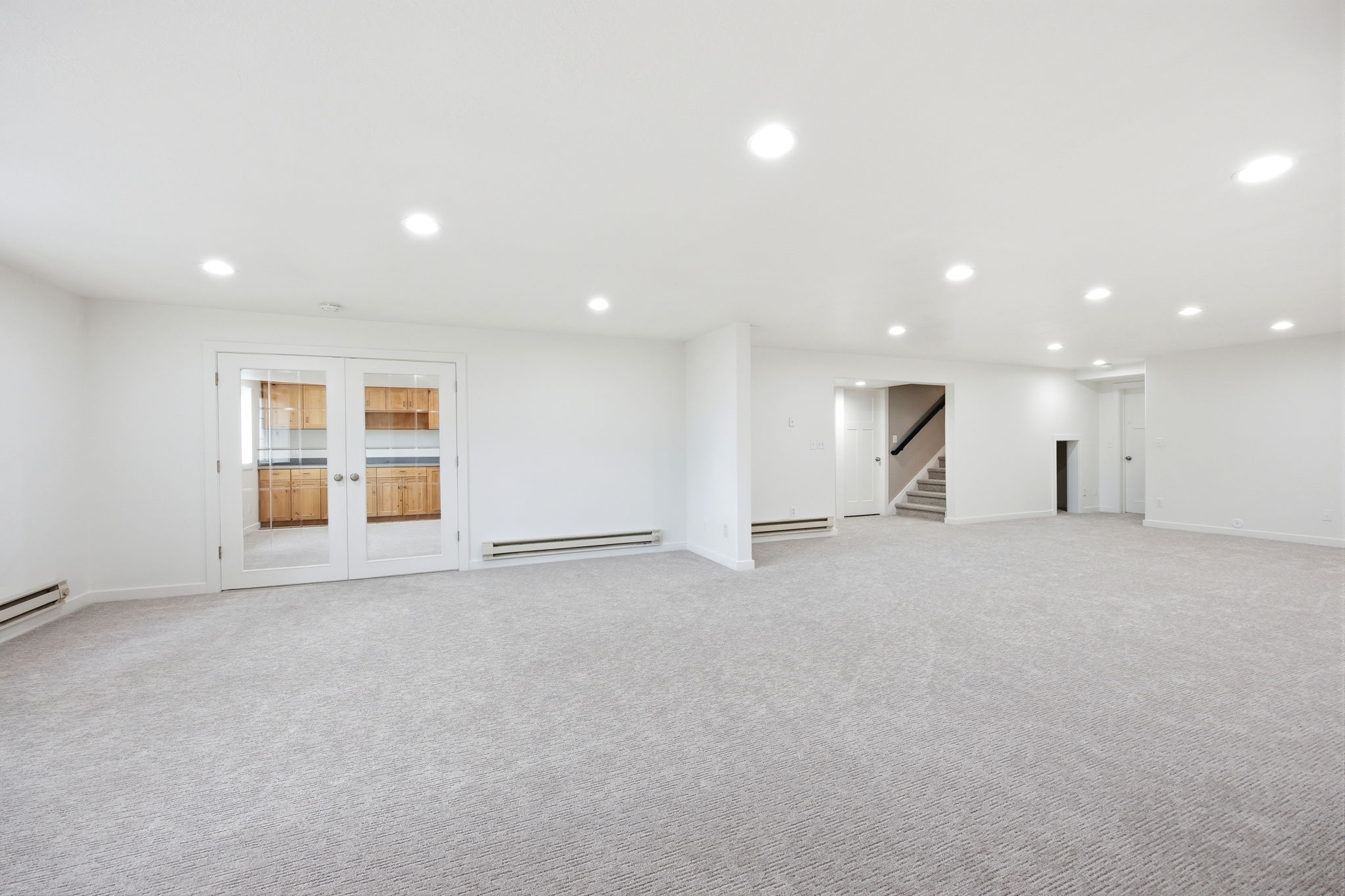 Expansive carpeted room with recessed lighting and white walls