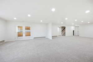 Expansive carpeted room with recessed lighting and white walls