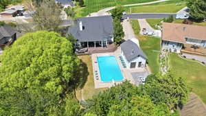Property featuring an inground swimming pool with a diving board, a separate pool house with a garage door, a substantial rear deck, and mature landscaping