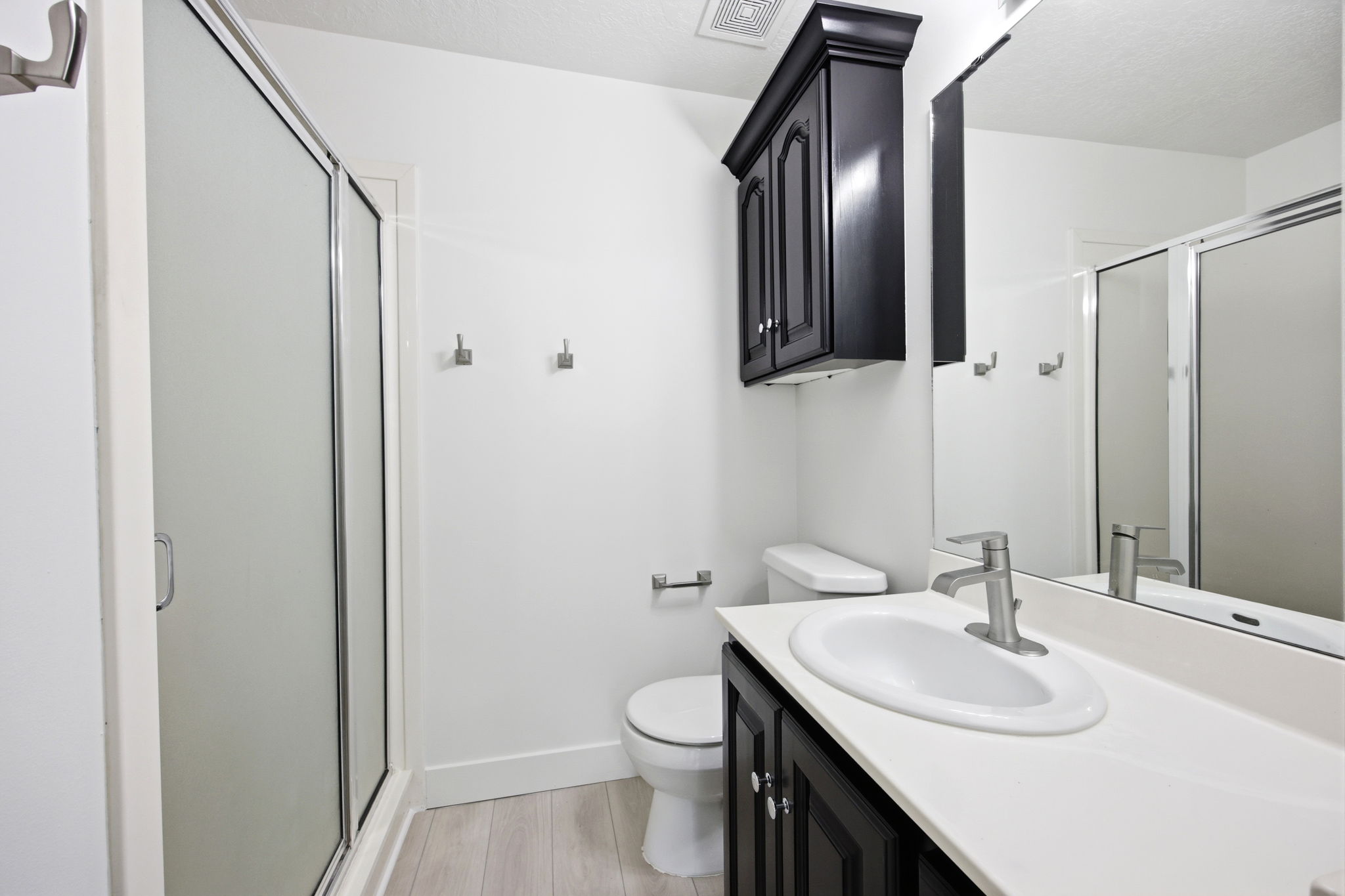 Bathroom featuring a white vanity countertop, undermount sink, and black wood-finish cabinetry